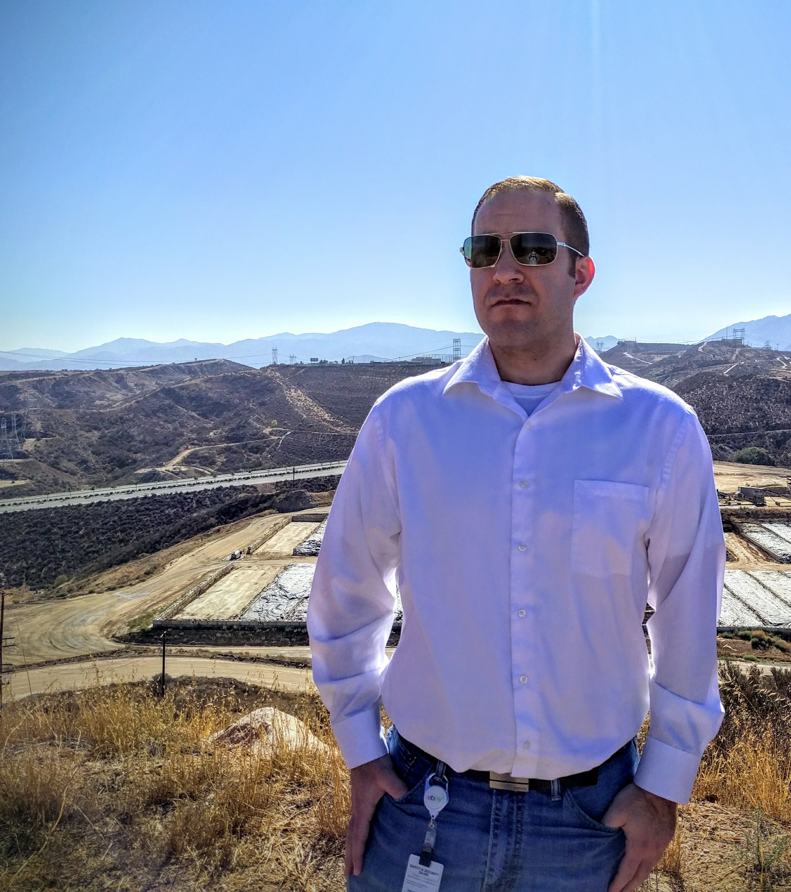 Brett Haddoak standing on a ridge above the Bermite property, with the Santa Clarita Valley and mountains behind him.
